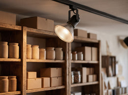 Ampoule halogène PAR38 E27 montée dans un spot noir sur rail, éclairant les étagères en bois d'une boutique – mise en situation