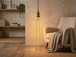 Ampoule tube T30 Robb allumée, suspendue près d'un fauteuil beige dans un salon au parquet en bois