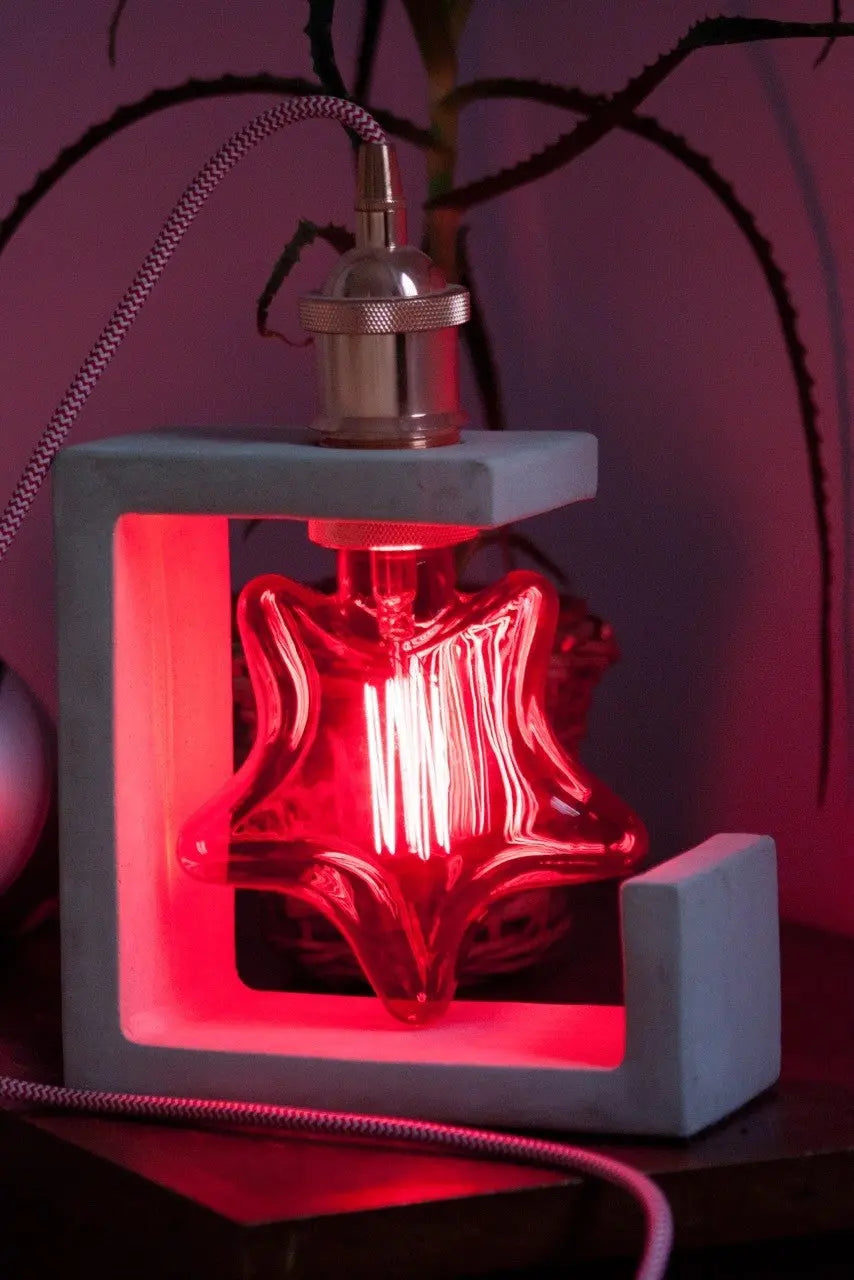 Ampoule étoile rouge E27 allumée dans une lampe à poser en béton, avec douille métallique et câble textile tressé