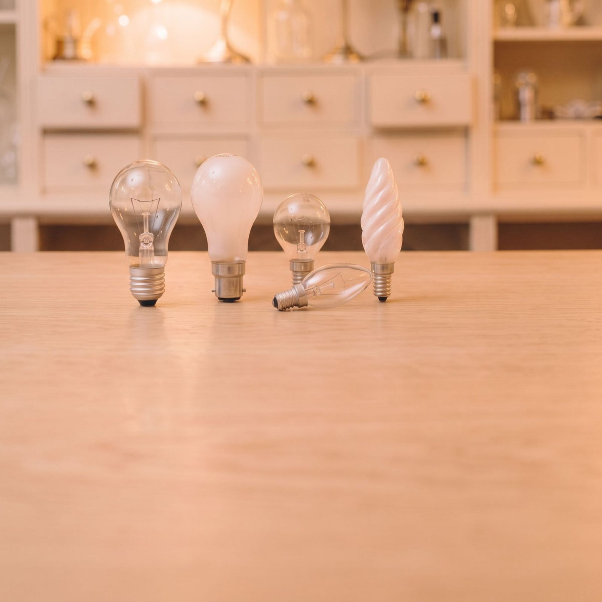 Ampoules à incandescence poire, sphérique et flamme en verre clair et dépoli, posées sur un comptoir en chêne clair