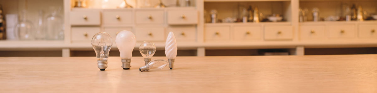 Ampoules à incandescence poire, sphérique et flamme en verre clair et dépoli, posées sur un comptoir en chêne clair
